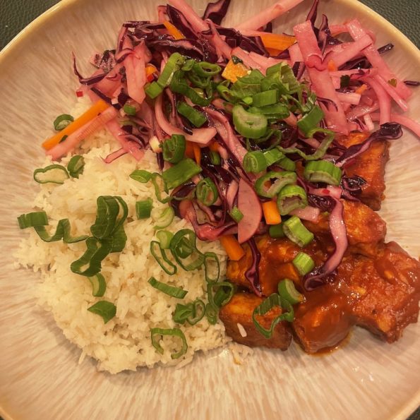 Ein Teller mit Gochujang Tempeh, Reis und Krautsalat