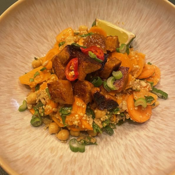 Salat mit Quinoa, Kichererbsen, Karotten und Kürbiskernen, darauf gebratener Seitan