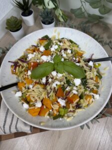 Herbstlicher Orzo-Salat mit Kürbis, Lauch, roter Zwiebel und veganem Feta in einer großen Schüssel