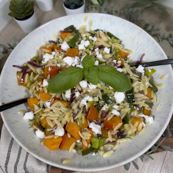 Herbstlicher Orzo-Salat mit Kürbis, Lauch, roter Zwiebel und veganem Feta in einer großen Schüssel