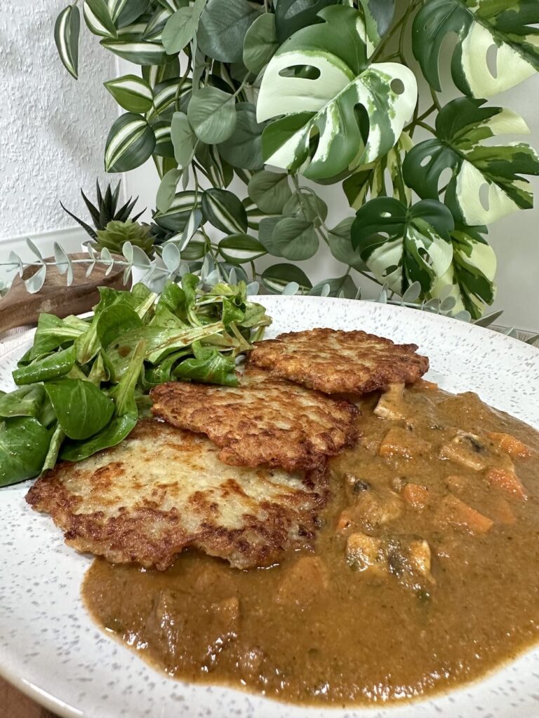 Kartoffelpuffer mit Feldsalat und Pilzsoße auf einem Teller angerichtet